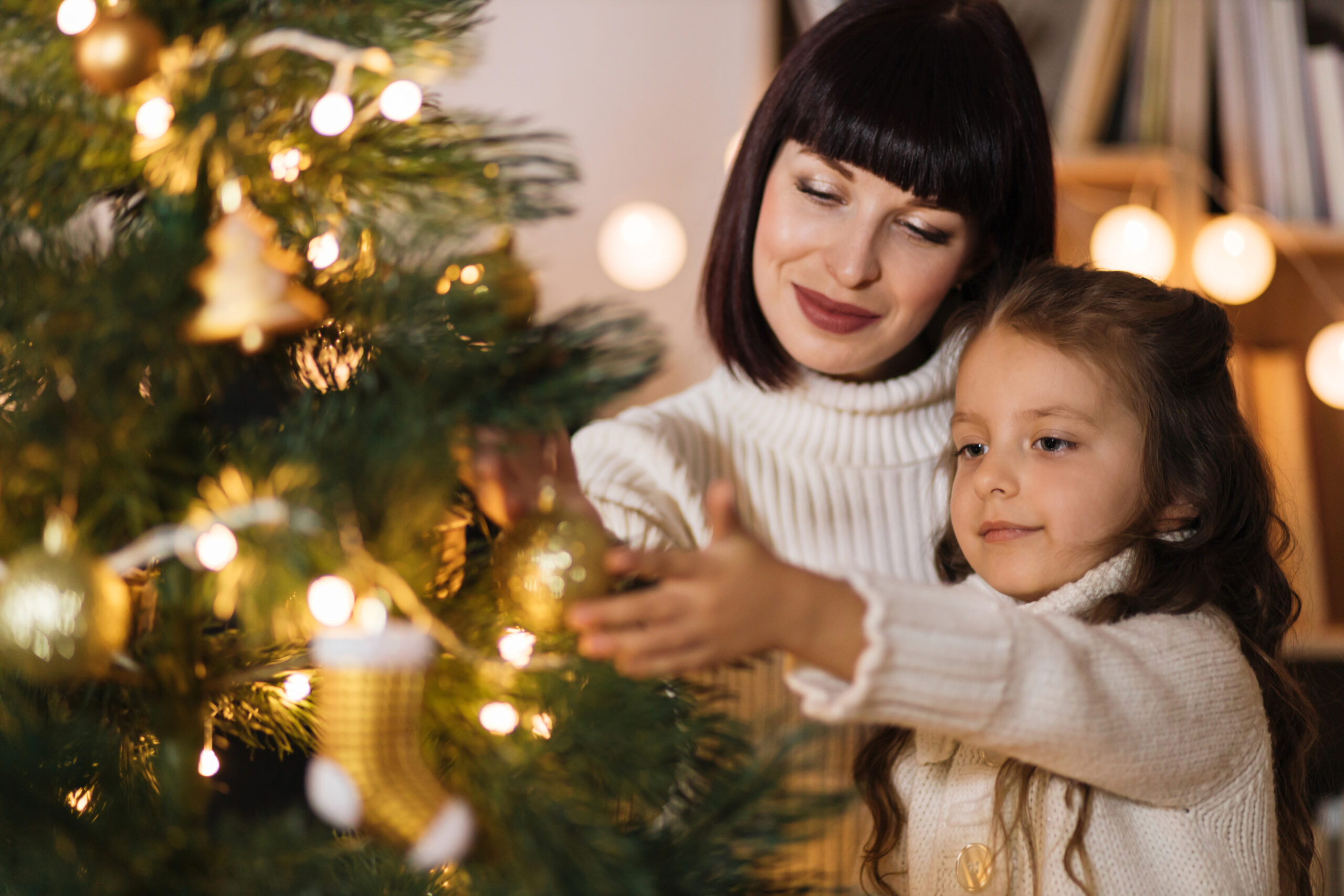 Mother and daughter holding decoration for Christmas tree.